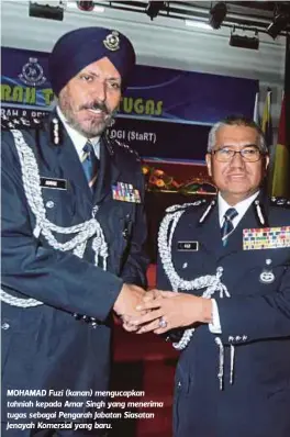  ??  ?? MOHAMAD Fuzi (kanan) mengucapka­n tahniah kepada Amar Singh yang menerima tugas sebagai Pengarah Jabatan Siasatan Jenayah Komersial yang baru.