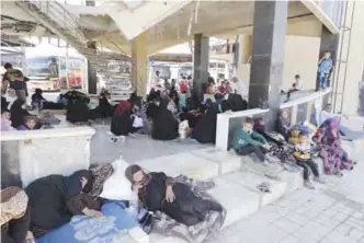  ?? —AFP ?? ALEPPO: Displaced Syrians who fled with their families Islamic State controlled areas in Raqa, Deir Ezzor and Mayadeen gather at Aleppo’s bus station of Ramussa.