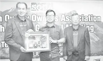  ??  ?? Ringo (left) presenting a souvenir to Junz Wong (centre) during the AGM recently.