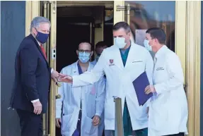  ?? JACQUELYN MARTIN/AP ?? White House Chief of Staff Mark Meadows, left, holds the door for Dr. Sean Conley, physician to President Donald Trump, right, and other doctors, as they walk out to brief reporters on Sunday.