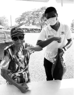  ??  ?? Leon Malcolm greets an elderly resident and gives her a care package.