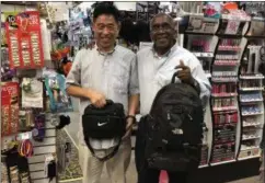  ?? NICHOLAS BUONANNO — NBUONANNO@ TROYRECORD. COM ?? Billy Carter of Kingdom Ministries, right, displays a backpack that he will be giving away with Nite Owl News owner Yong Rhee.