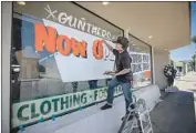  ?? Allen J. Schaben Los Angeles Times ?? WORKER AKIHIRO Tsuneizumi paints a window sign at clothing store Gunthers Supply in Santa Ana.