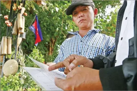  ?? HENG CHIVOAN ?? An official checks the documents of an ethinicall­y Vietnamese villager during an immigratio­n crackdown yesterday in Kampong Chhnang province.