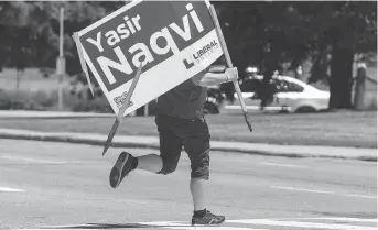  ?? ERROL McGIHON ?? A worker runs across Carling Avenue on Friday with a Yasir Naqvi campaign sign he removed from a property in the Ottawa-Centre riding, where the Liberal candidate was defeated in the provincial election.
