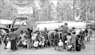  ?? Reuters photo ?? Rohingya refugees carry their containers as they wait to fill them up with drinking water from a tanker at Kutupalong refugee camp near Cox’s Bazar, Bangladesh.—