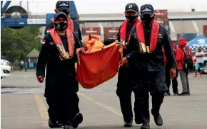  ?? AP ?? Workers at the search and rescue command center at Tanjung Priok Port, in Jakarta, carry debris found in the waters around the location of Saturday’s crash of a Sriwijaya Air passenger jet.