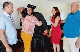  ?? DANA JENSEN THE DAY ?? Wilfredo Dolores hugs his aunt Nery Santana with, from left, uncle Ricardo Francisco, his mother, Sandra Santana, and grandfathe­r Miguel Santana looking on after watching his Three Rivers Community College graduation ceremony Saturday at home in New London.