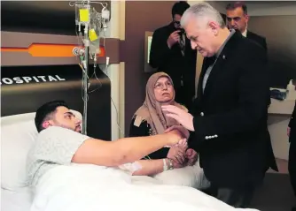  ?? AP Photo ?? Turkey’s prime minister Binali Yildirim speaks to a wounded man in hospital in Istanbul yesterday. He was injured during the attack in the Istanbul nightclub.