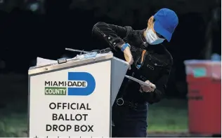  ?? PHOTO: REUTERS ?? Significan­t task . . . A poll worker casts a mailin ballot for a voter at a drivethrou­gh polling station at MiamiDade County Elections Department in Miami yesterday.