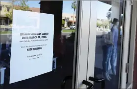  ?? RANDY HOEFT — THE YUMA SUN VIA AP ?? A sign on the door to American Eagle in The Village inside the Yuma Palms Regional Center states the store is closed until March 28, due to coronaviru­s and to “Keep Smiling!”.