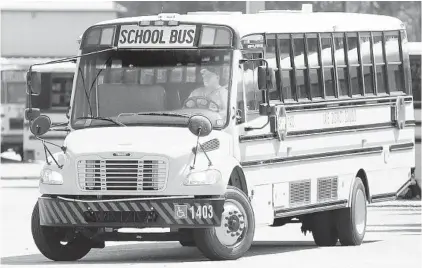  ?? STEPHEN M. DOWELL/ORLANDO SENTINEL ?? A bus driver guides a school bus in front of a row of school buses Aug. 30 at the Leesburg Bus Lot.