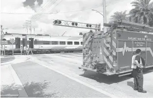  ?? WAYNE K. ROUSTAN/SUN SENTINEL PHOTOS ?? A Brightline passenger train and a freight train were stopped at the Northeast 38th Street railroad crossing in Oakland Park for several hours after the Brightline train struck a Maserati, officials said.