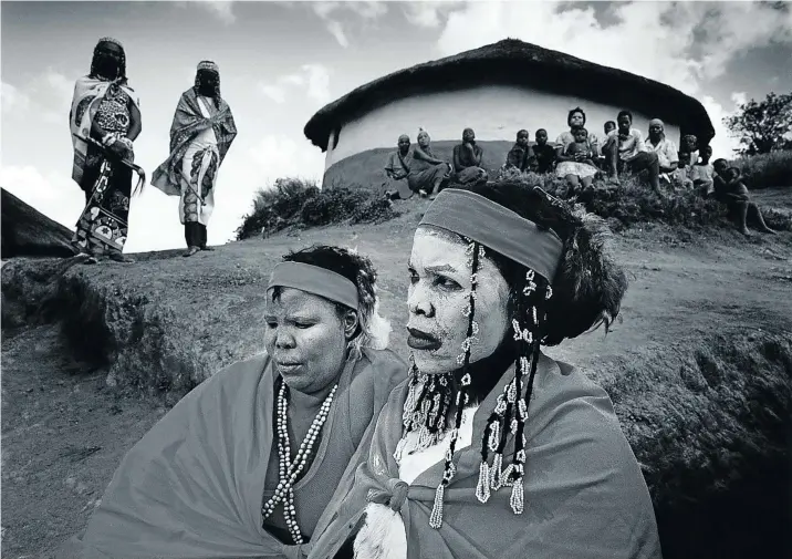  ??  ?? HEALING POWERS Young amathwasa (traditiona­l healer trainees) wait for the chief sangoma in a village in the hills above Gingindlov­u, KZN, 1981.