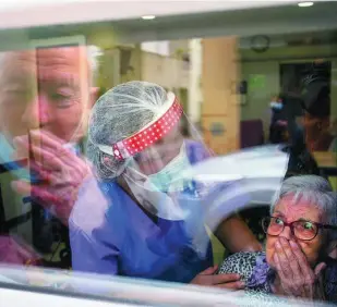  ?? AP ?? Javier Anto besa a su esposa, Carmen Panzano, a través del cristal de la residencia en la que ella vive