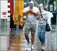  ?? AP/Miami Herald/CARL JUSTE ?? South Beach tourists brave the rain Monday as a tropical storm warning was issued for Miami Beach, Fla.