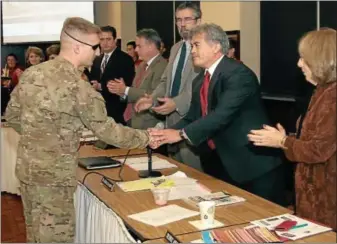  ?? Gazette staff photo by BOB RAINES ?? Upper Dublin Superinten­dent Michael Pladus shakes hands with Sgt. Eric Petersen following the presentati­on of the Flying Cardinal Award as the Upper Dublin School Board gives Peterson a standing ovation Monday evening. A 2005 graduate of Upper Dublin...