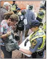  ?? AP/STEVE HELBER ?? Virginia State Police officers inspect bags Saturday at one of two checkpoint­s in downtown Charlottes­ville.