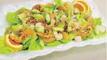  ??  ?? Spicy grilled shrimp is served on a bed of butter lettuce with hearts of palm, avocado and orange.