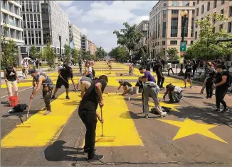  ?? TONI SANDYS / WASHINGTON POST ?? Local artists and public work crews paint “Black Lives Matter” on 16th Street near the White House on Friday, authorized by D.C. Mayor Muriel E. Bowser in renaming the street.