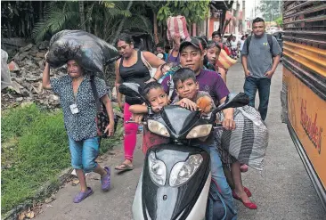  ?? [AP PHOTO] ?? Residents evacuate after a new flow of searing hot volcanic material moved down the slopes of the Volcano of Fire on Tuesday in Escuintla, Guatemala. The volcano exploded Sunday, sending down hot clouds of gas and ash that killed at least 70 people in...