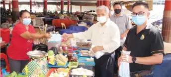  ??  ?? Lating hands over face masks to a hawker. Also seen are Jabang (right) and Wong.