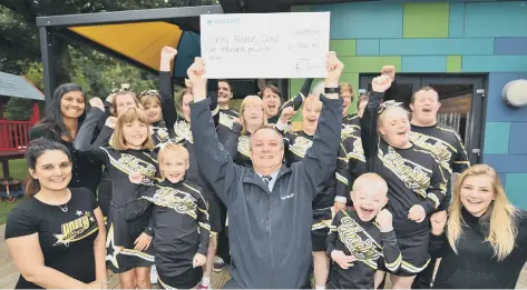  ??  ?? Unity All Stars Gold cheerleade­rs group receive £1,000 cheque from Mick George key account manager Andrew Goode from the Skip of Gold award