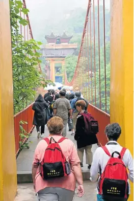  ?? Picture: GALLO IMAGES/ALAMY ?? SPOOKED: Tourists cross the hanging bridge from the ‘ghost city’ of Fengdu