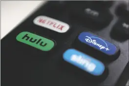  ??  ?? IN THIS AUG. 13, 2020 FILE PHOTO, the logos for Netflix, Hulu, Disney Plus and Sling TV are pictured on a remote control in Portland, Ore. As movie theaters closed and lockdowns descended across the country, people turned to the ever-growing number of video streaming services for entertainm­ent.