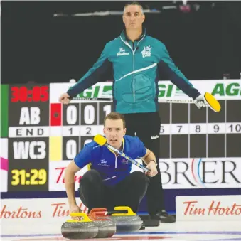  ?? MICHAEL BURNS CURLING CANADA ?? Alberta skip Brendan Bottcher gets low to watch an incoming stone as Wayne Middaugh, skip of Wild Card 3, watches the line from above. Bottcher won, pushing his record to 3-1.