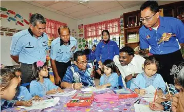  ??  ?? Helping hand: Khaled (centre) helping a pupil with her work at Tabika Kemas Taman Rinting yesterday. Looking on is Permas assemblyma­n Datuk M.M. Samy (second from right).
