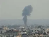  ?? HATEM MOUSSA/AP ?? Smoke rises from a building hit by Israeli airstrikes on Friday in Gaza City. Palestinia­n officials said a senior militant was among at least 10 people killed.