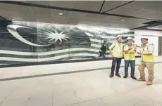  ??  ?? The undergroun­d team standing at one of the feature walls at the Merdeka Station featuring the Jalur Gemilang