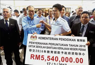  ??  ?? Important contributi­on: Chong (in T-shirt) handing the allocation for over 100 Chinese vernacular schools in Perak to state exco member Datuk Mah Hang Soon.