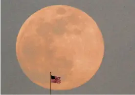  ?? Photo / AP ?? A US flag on top of the Kansas City city hall building stands against the rising full moon.