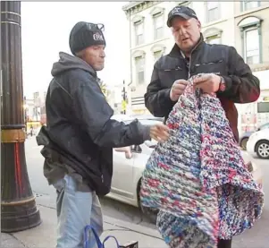  ?? HAMILTON SPECTATOR FILE PHOTO ?? Middle: Roger Boyd, who operates Men’s Street Ministry, shows a man on James Street one the “street beds” made from woven plastic milk bags that provides some padding and insulation from the ground.