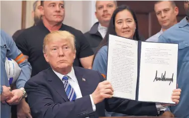  ?? SUSAN WALSH/ASSOCIATED PRESS ?? President Trump holds up his just-signed proclamati­on placing a tariff on aluminum imports at the White House on Thursday. He also signed a companion proclamati­on placing a tariff on steel imports.