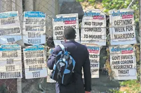  ?? [TSVANGIRAY­I MUKWAZHI/ THE ASSOCIATED PRESS] ?? A man reads newspaper headlines Sunday on a street of Harare, Zimbabwe.