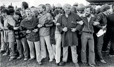  ?? JOHN SELKIRK ?? Protesters form a tight bond in the middle of the pitch after running on to Rugby Park, Hamilton, before the start of the Waikato v Springboks game on July 25, 1981. The match was cancelled.