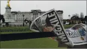  ?? KIRSTY WIGGLESWOR­TH — THE ASSOCIATED PRESS ?? A newspaper is blown by the wind after it is placed on a railing by a television crew outside Buckingham Palace in London on Monday.