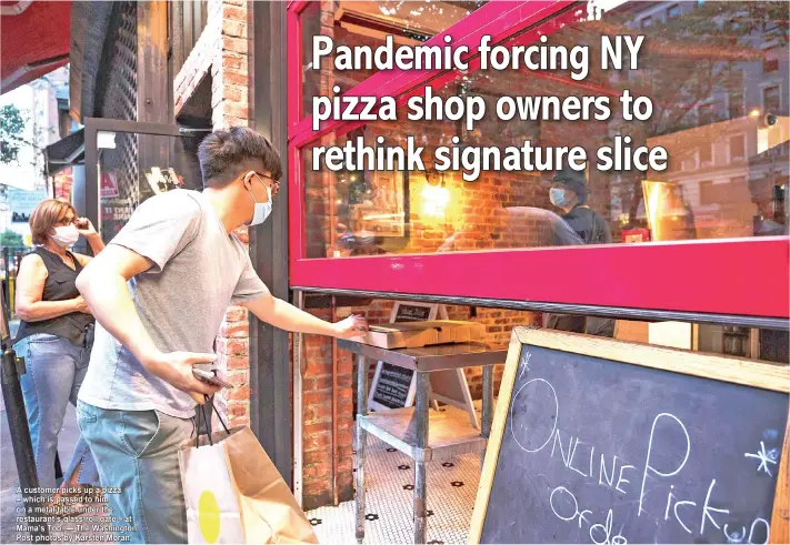  ??  ?? A customer picks up a pizza – which is passed to him on a metal table under the restaurant’s glass roll gate – at Mama’s Too. — The Washington Post photos by Karsten Moran