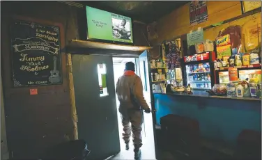  ??  ?? A customer walks out of the Blue Front Cafe in while a YouTube video of owner and bluesman Holmes plays on the television. The cafe is among the oldest surviving juke joints in the state, having been founded by Holmes parents.