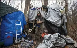  ?? PHOTOS BY JOHN MUNSON — THE ASSOCIATED PRESS ?? Jose Ortiz eats a boxed meal delivered by volunteers to the residence he built in the homeless encampment known as the Jungle in Ithaca, N.Y., on Dec. 7. When Jose Ortiz tested positive for COVID-19 last month, he was able to isolate at his elaboratel­y crafted shelter, which includes a “treehouse” about waist-high with a wood stove pipe and a tree protruding from the tarp-covered top.