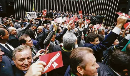  ?? Pedro Ladeira/Folhapress ?? Deputados favoráveis e contrários ao impeachmen­t protestam durante sessão no plenário da Câmara com cartazes