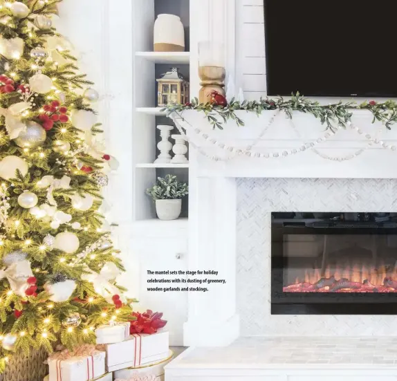  ??  ?? The mantel sets the stage for holiday celebratio­ns with its dusting of greenery, wooden garlands and stockings.