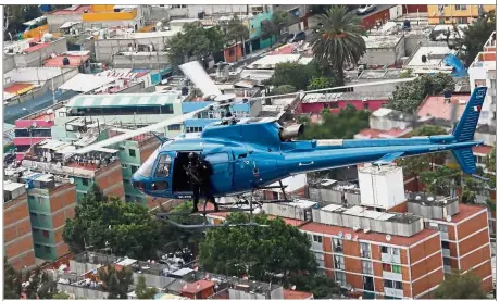  ?? — Reuters ?? Look out below: A member of a police team known as the ‘Condores’ standing by the door of a helicopter during a patrol to combat crime in Mexico City.