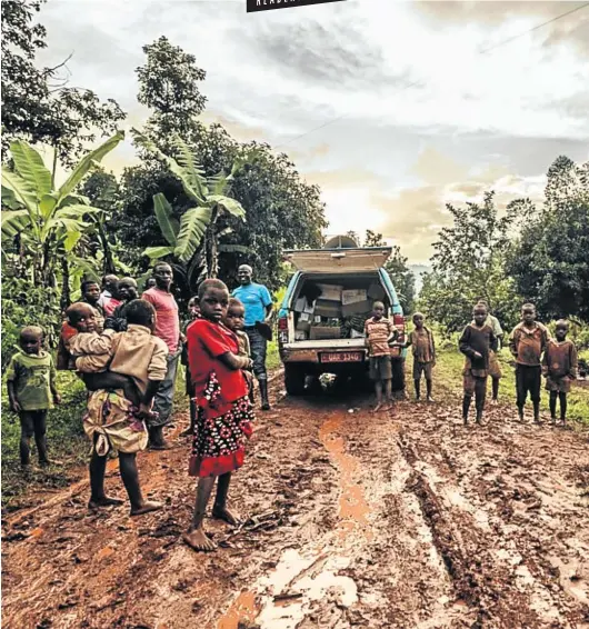  ?? Pictures: Henri Kitti ?? MUD BROTHERS Tuk, in a blue T-shirt, stands by the car after it got stuck on a muddy road in Kabuli — with some villagers who’ve come out to see what’s happening.