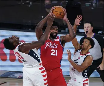  ?? ASHLEY LANDIS - ASSOCIATED PRESS POOL ?? 76ers center Joel Embiid, center, fends off Washington Wizards center Thomas Bryant, left, and guard Jerome Robinson, right, Wednesday night. Embiid was up to the physical challenge to the lead the 76ers to a 107-98 victory.