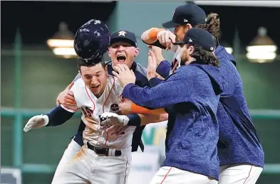  ?? MATT SLOCUM / AP ?? Alex Bergman is mobbed by Houston Astros teammates after his walk-off single in the 10th inning beat the Los Angeles Dodgers 13-12 in Game 5 of the World Series at Minute Maid Park in Houston on Sunday. The Astros now lead the best-of-seven series 3-2,...