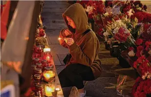  ?? Alexander Zemlianich­enko/Associated Press ?? A young woman lights a candle Tuesday at an informal street memorial near the Kremlin for Wagner Group members killed in a plane crash.